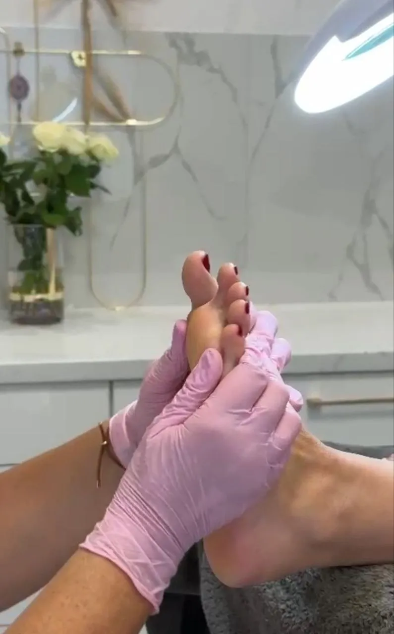 Sanfte Fußmassage und Untersuchung durch die Behandlerin mit Handschuhen